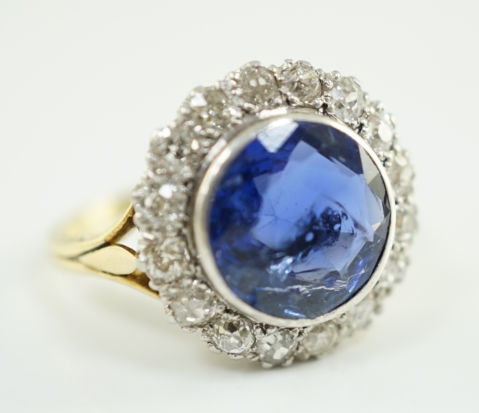 A gold and single stone round cut sapphire set dress ring, with diamond set border